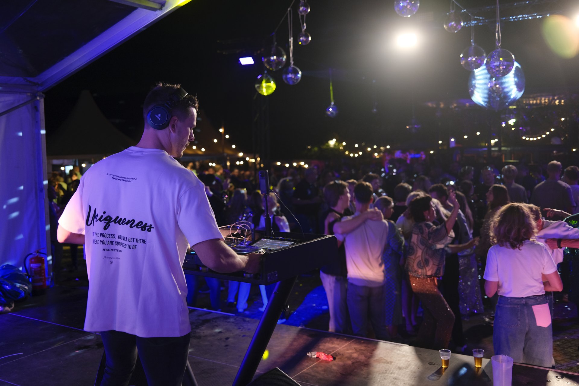 DJ Gluutje achter de draaitafel met sfeerverlichting en een volle dansvloer