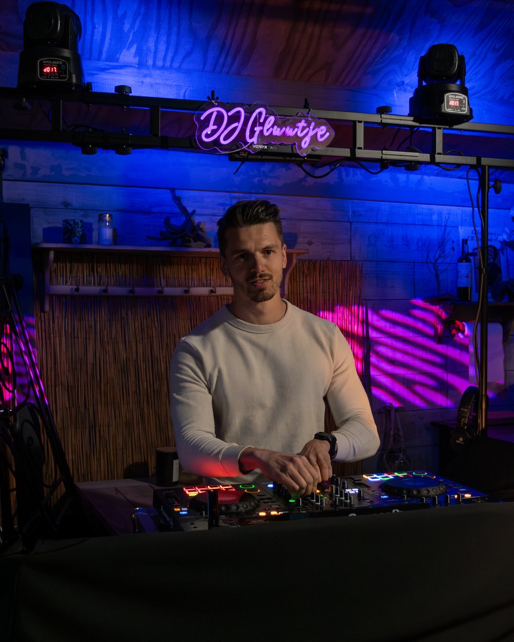 Portretfoto DJ Gluutje achter de draaitafel met DJ Gluutje neon