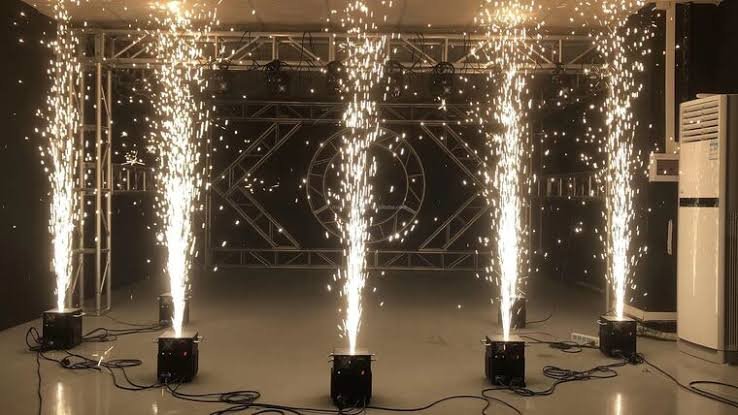 Vijf cold sparkler machines die fonteinen van koude vonken creëren op een podium