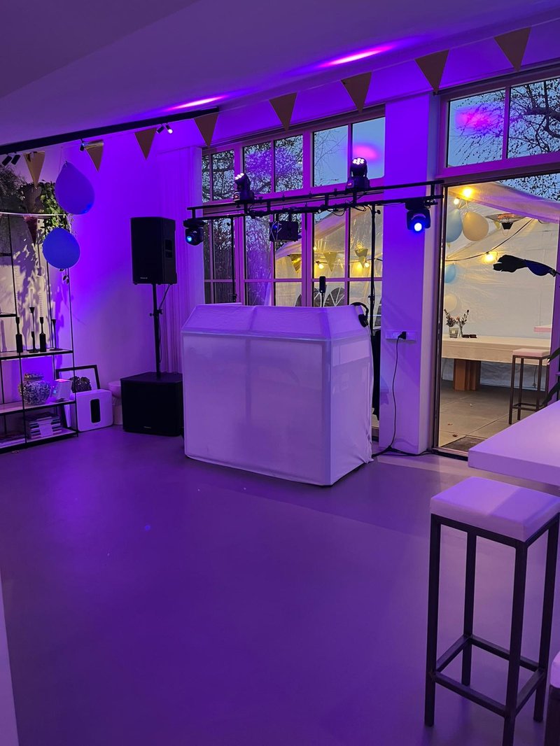 Exclusive DJ setup met paarse uplights en lichtbrug